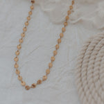 Gold necklace on a textured white surface