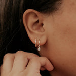 Close-up of a person wearing a gold earring with three small stones.