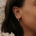Close-up of an ear wearing a gold earring with a blurred background