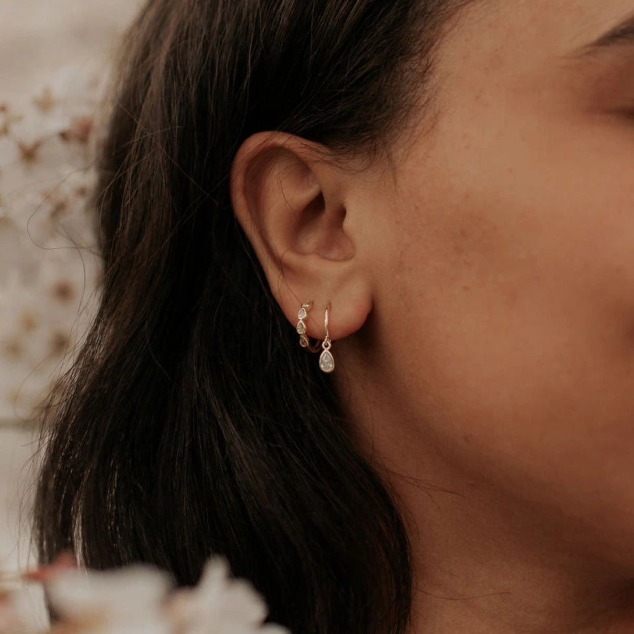 Close-up of a person wearing two earrings with a blurred background