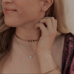 Woman adjusting her earring with a neutral background