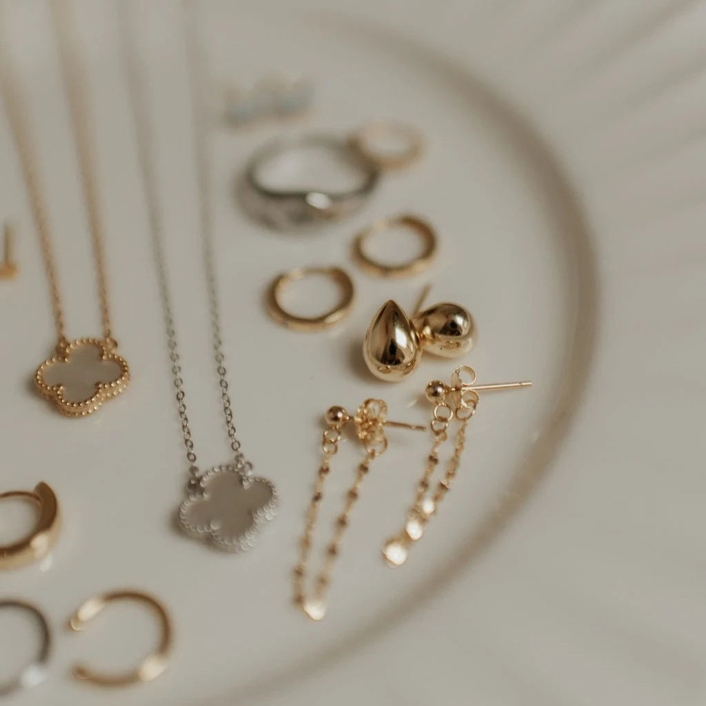 Collection of gold and silver jewelry on a textured surface
