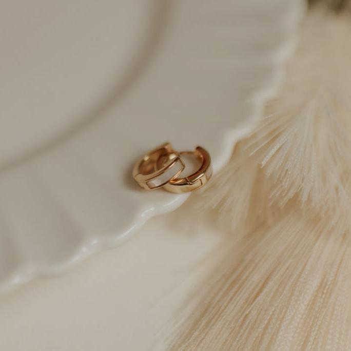 Gold hoop earrings on a textured beige surface