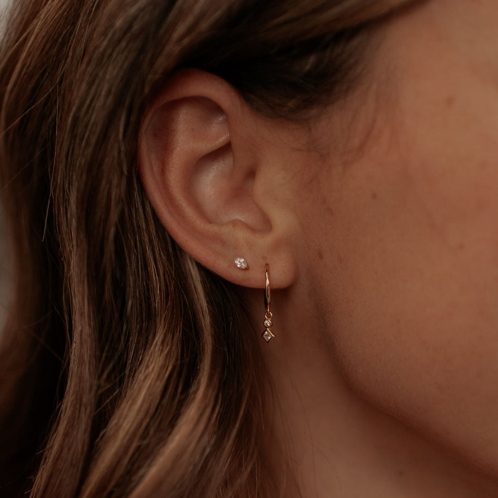 Close-up of an ear wearing gold earrings with a blurred background