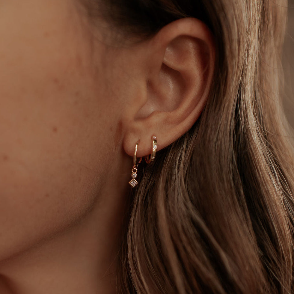 Close-up of an ear wearing a small earring with a blurred background