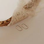 Silver hoop earrings on a soft beige fabric background