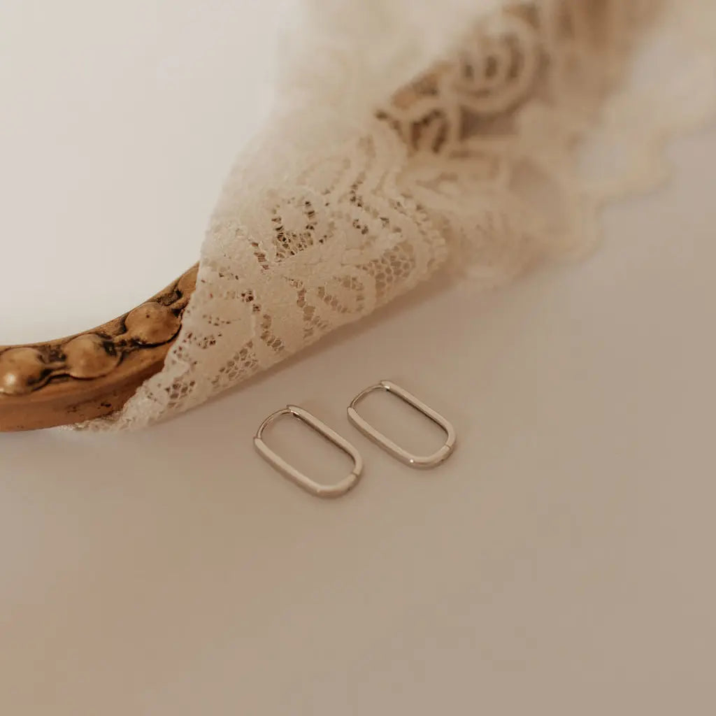 Silver hoop earrings on a soft beige fabric background