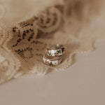 Two floral-patterned earings on a lace fabric background