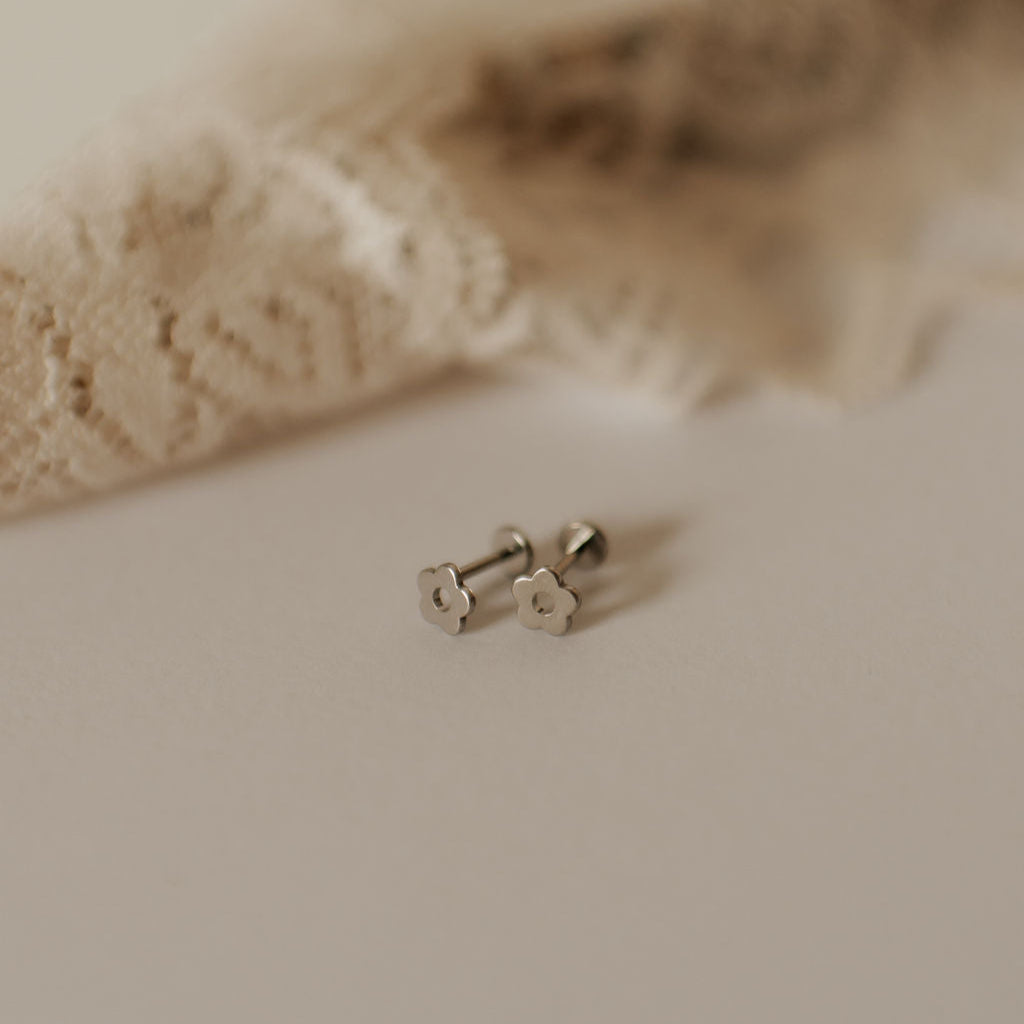 Pair of silver earrings on a soft beige fabric background