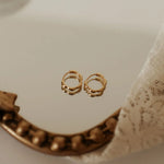 Gold hoop earrings on a textured surface with lace fabric