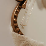 Gold necklace with a teardrop pendant on a textured surface
