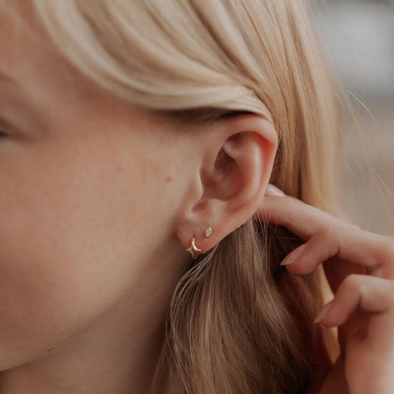 Close-up of a person wearing a gold earring with a blurred background