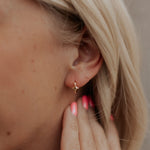 Close-up of a person wearing a gold star-shaped earring with blurred background