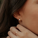 Close-up of a person wearing a gold teardrop earring with a blurred background