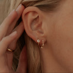 Load image into Gallery viewer, Close-up of an ear with gold hoop earrings and a hand adjusting hair.
