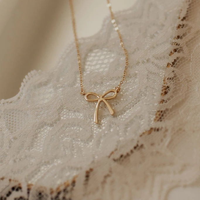 Gold bow-shaped necklace on a lace fabric background