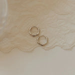 Gold hoop earrings on a textured beige fabric background