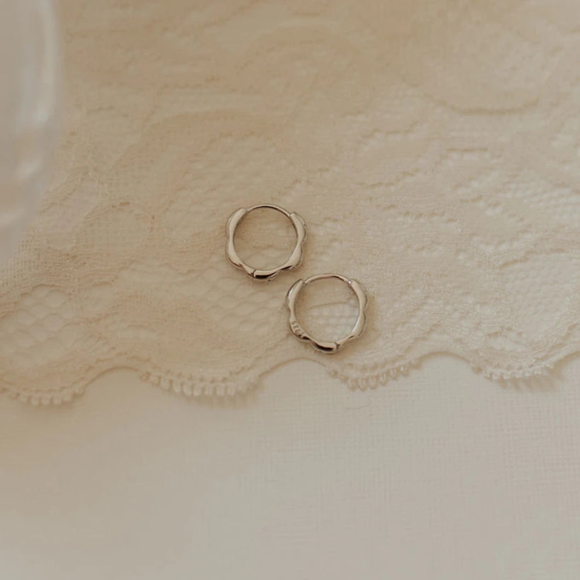 Gold hoop earrings on a textured beige fabric background