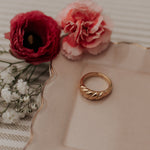 Load image into Gallery viewer, Gold ring on a decorative plate with red and pink flowers
