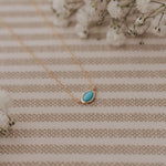 Necklace with a turquoise pendant on a striped fabric background