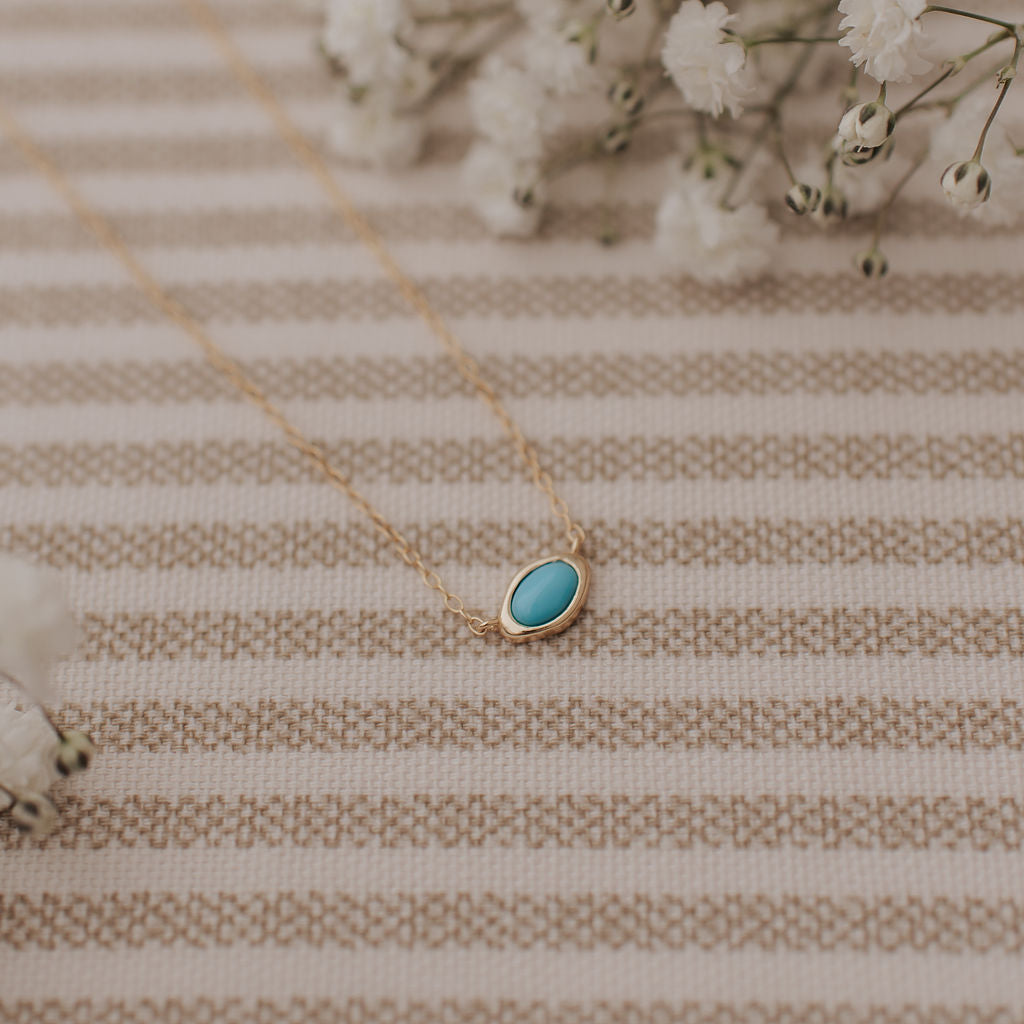 Necklace with a turquoise pendant on a striped fabric background