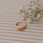 Gold ring on a beige striped fabric background with small white flowers.