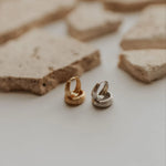 Two hoop earrings on a textured surface
