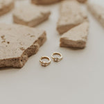 Gold hoop earrings on a textured stone surface