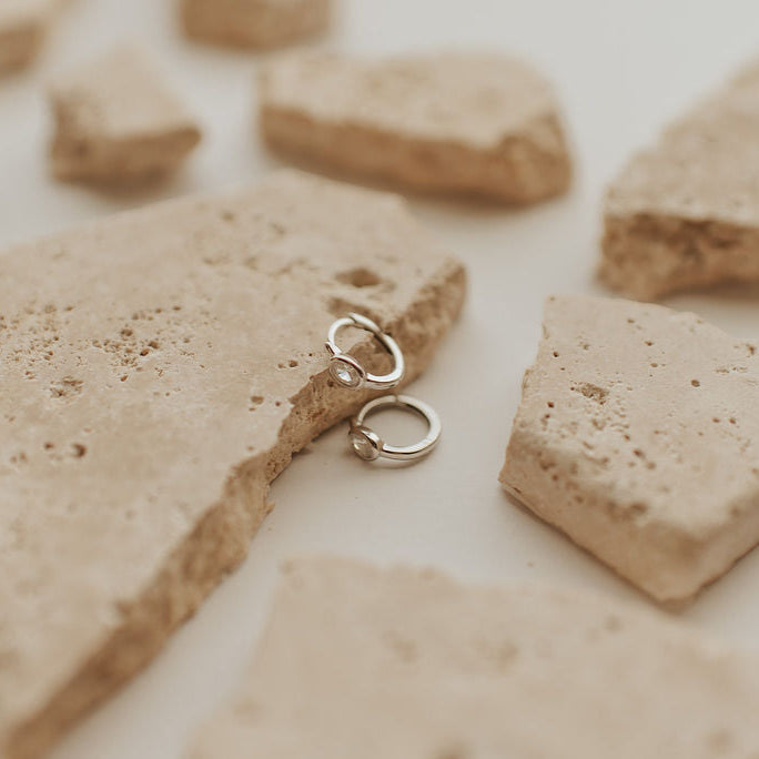 Silver earrings on a textured beige surface