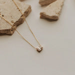 Gold necklace with a diamond pendant on a neutral background