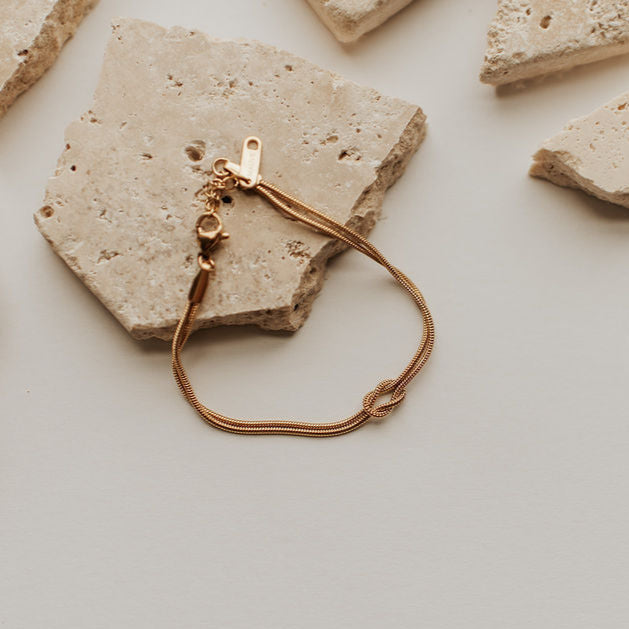 Gold bracelet on a textured beige stone surface