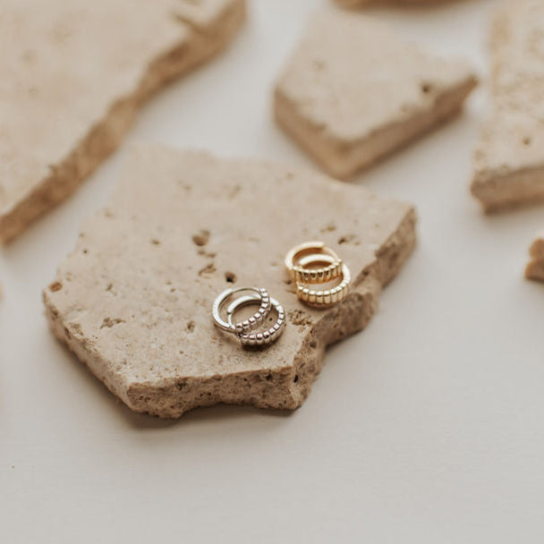 Two gold rings on a piece of beige stone with more stone pieces around.