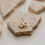 Load image into Gallery viewer, Gold earrings on a rough stone surface

