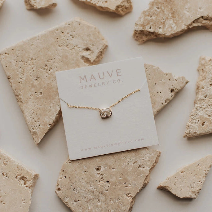 Gold necklace on a Mauve Jewelry Co. card with stone background