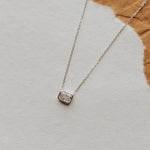 Silver necklace with a pendant on a textured surface