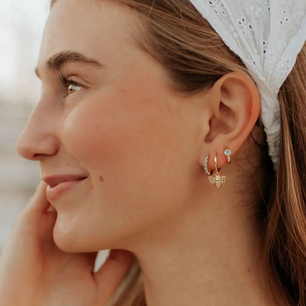 Close-up of a woman wearing gold earrings with a blurred background