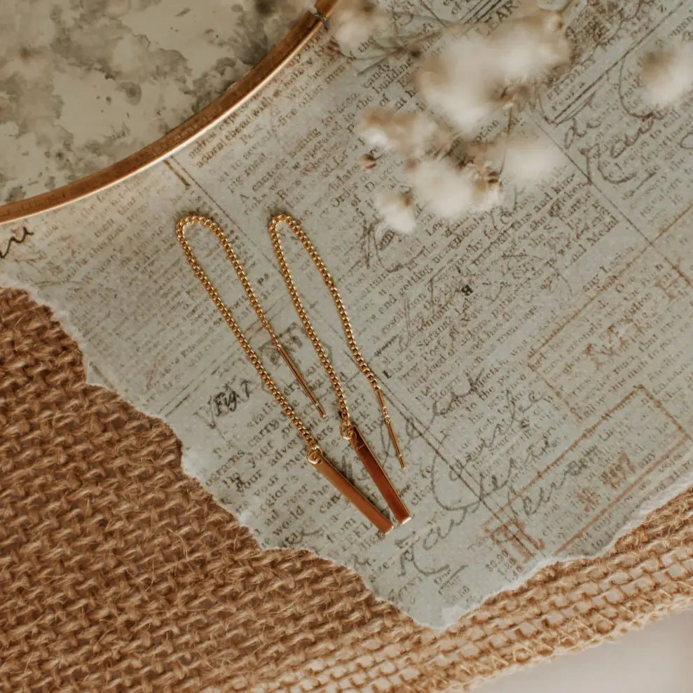 Gold necklace on a textured surface with cotton flowers
