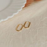 Gold hoop earrings on a textured beige surface