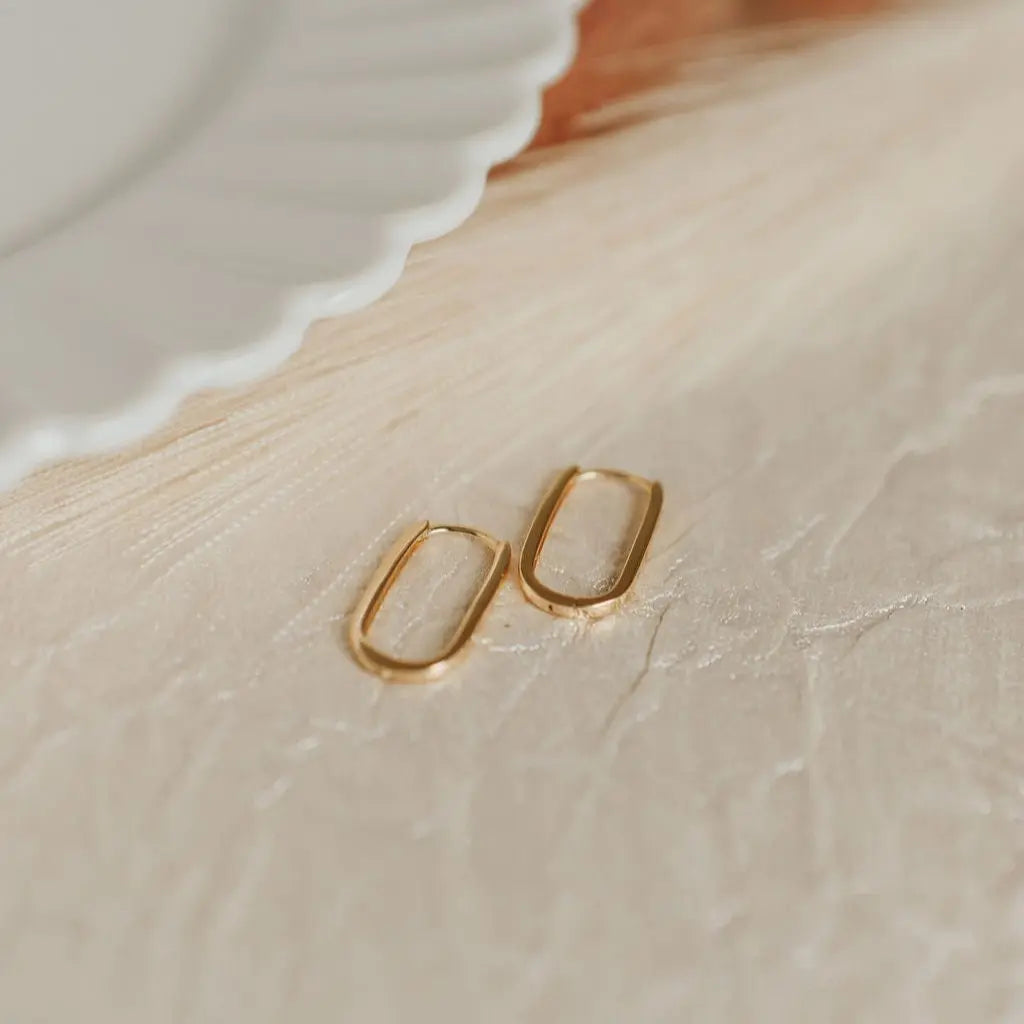 Gold hoop earrings on a textured beige surface