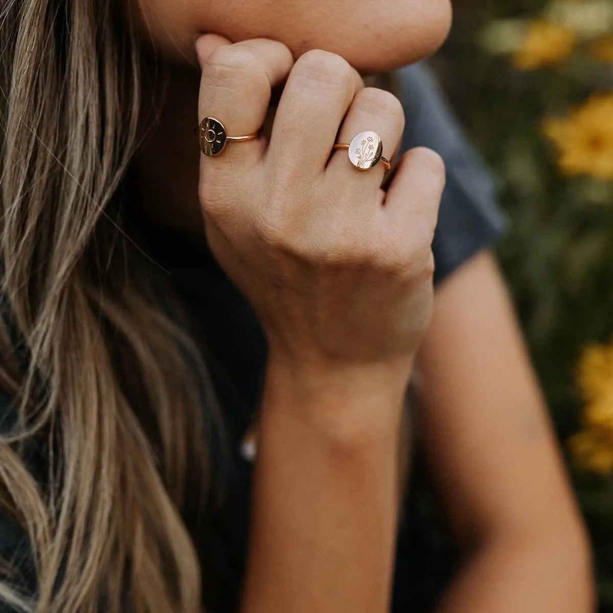 Close-up of a person's hand with two rings, blurred background