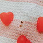 Heart-shaped earrings on a textured fabric background with red hearts.