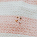 Heart-shaped earrings on a textured pink and white fabric background