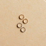 Pair of gold hoop earrings on a beige fabric background