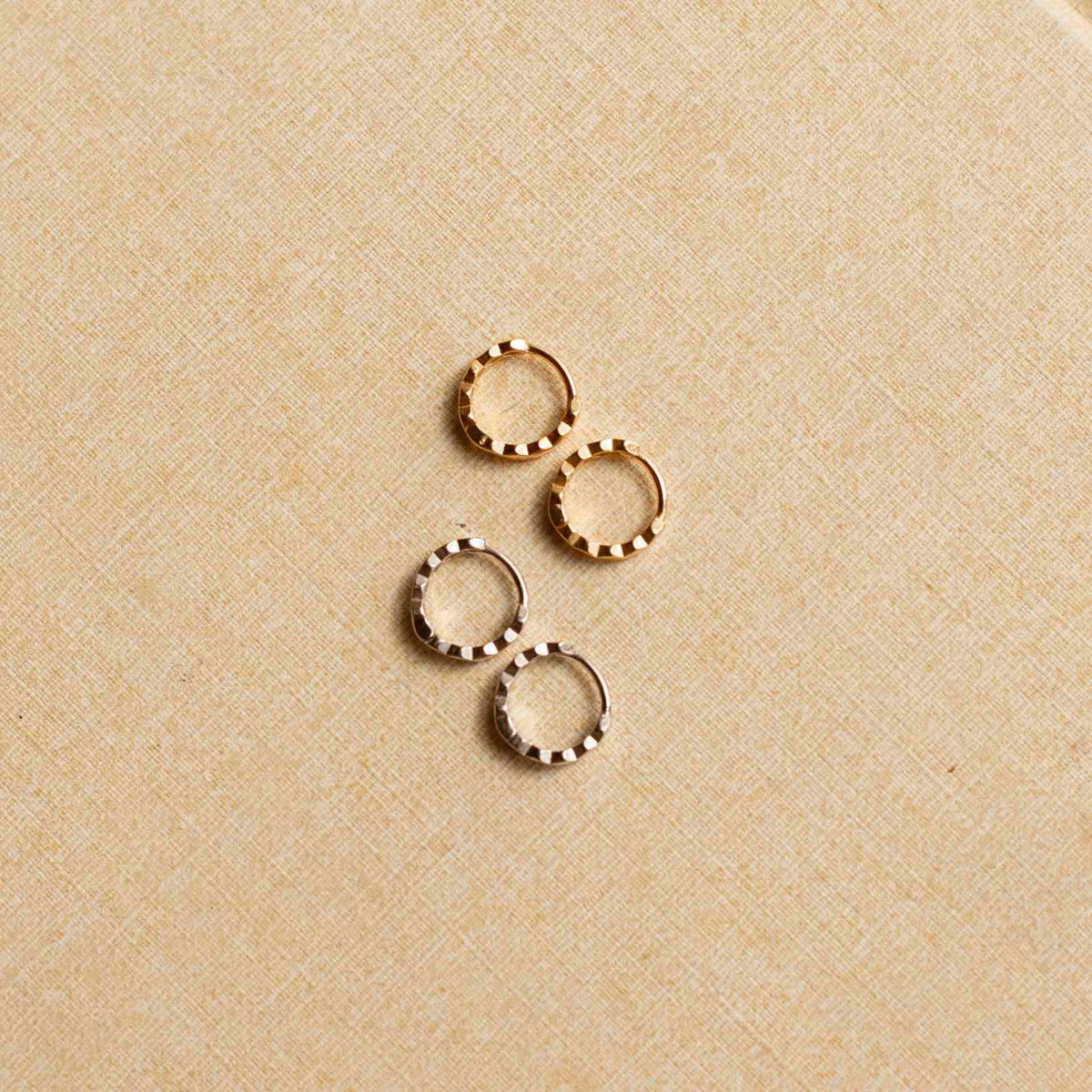 Pair of gold hoop earrings on a beige fabric background