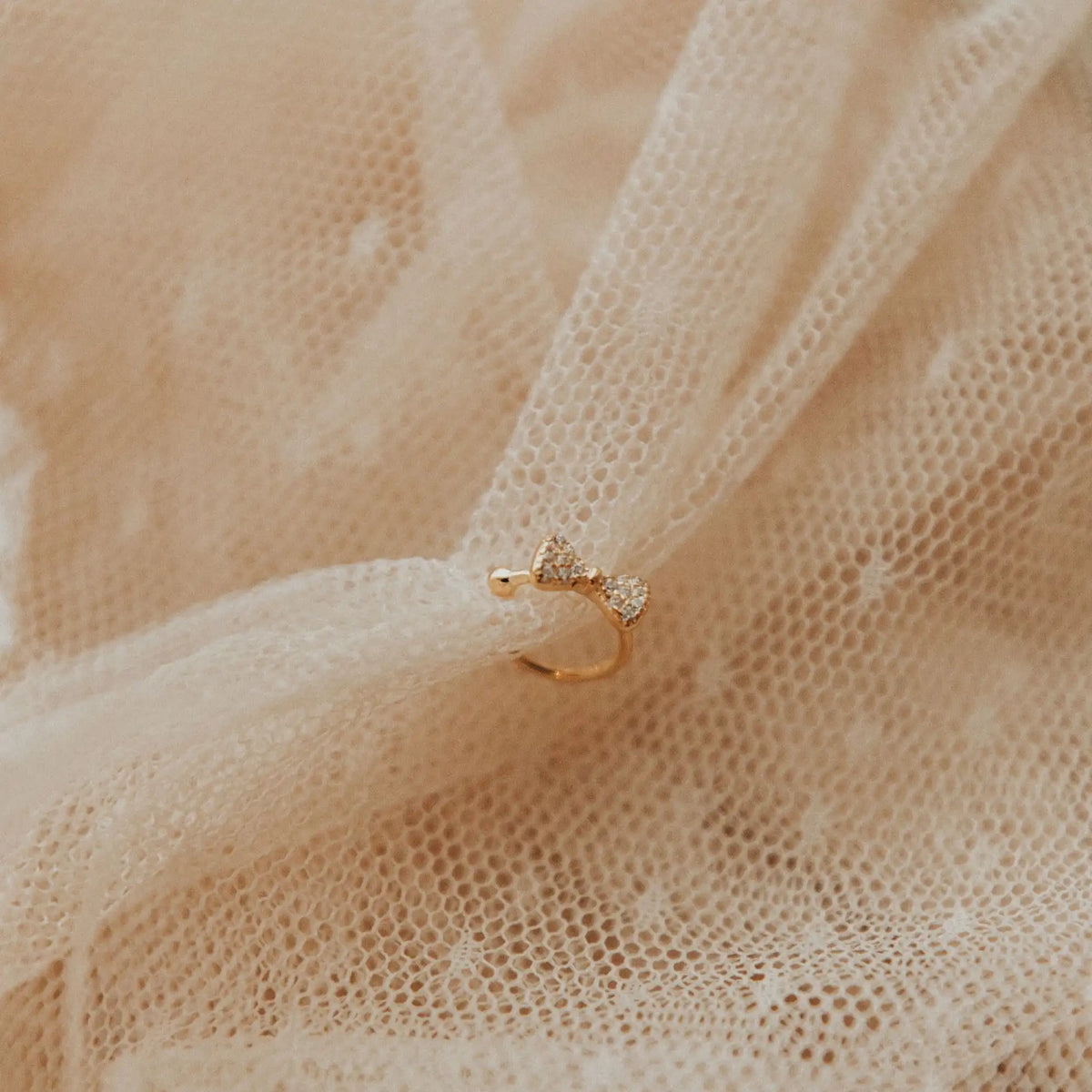 Gold ear cuff with a diamond on beige fabric