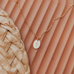 Gold necklace with a cross pendant on a textured brown surface