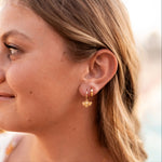 Close-up of a woman wearing gold bee-shaped earrings with a blurred background