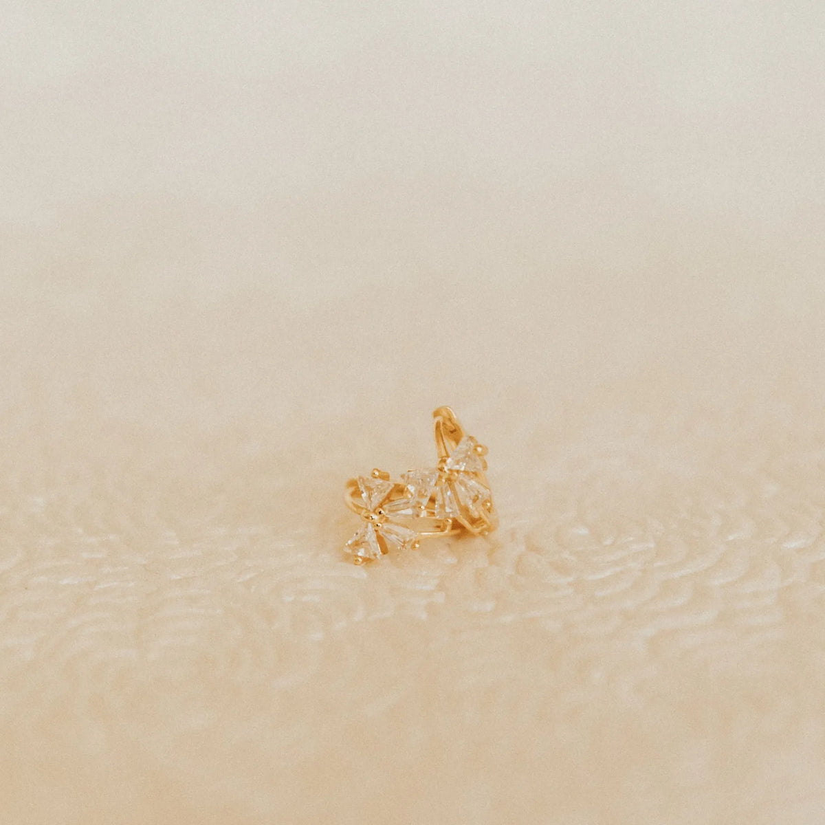 Gold earing on a beige background