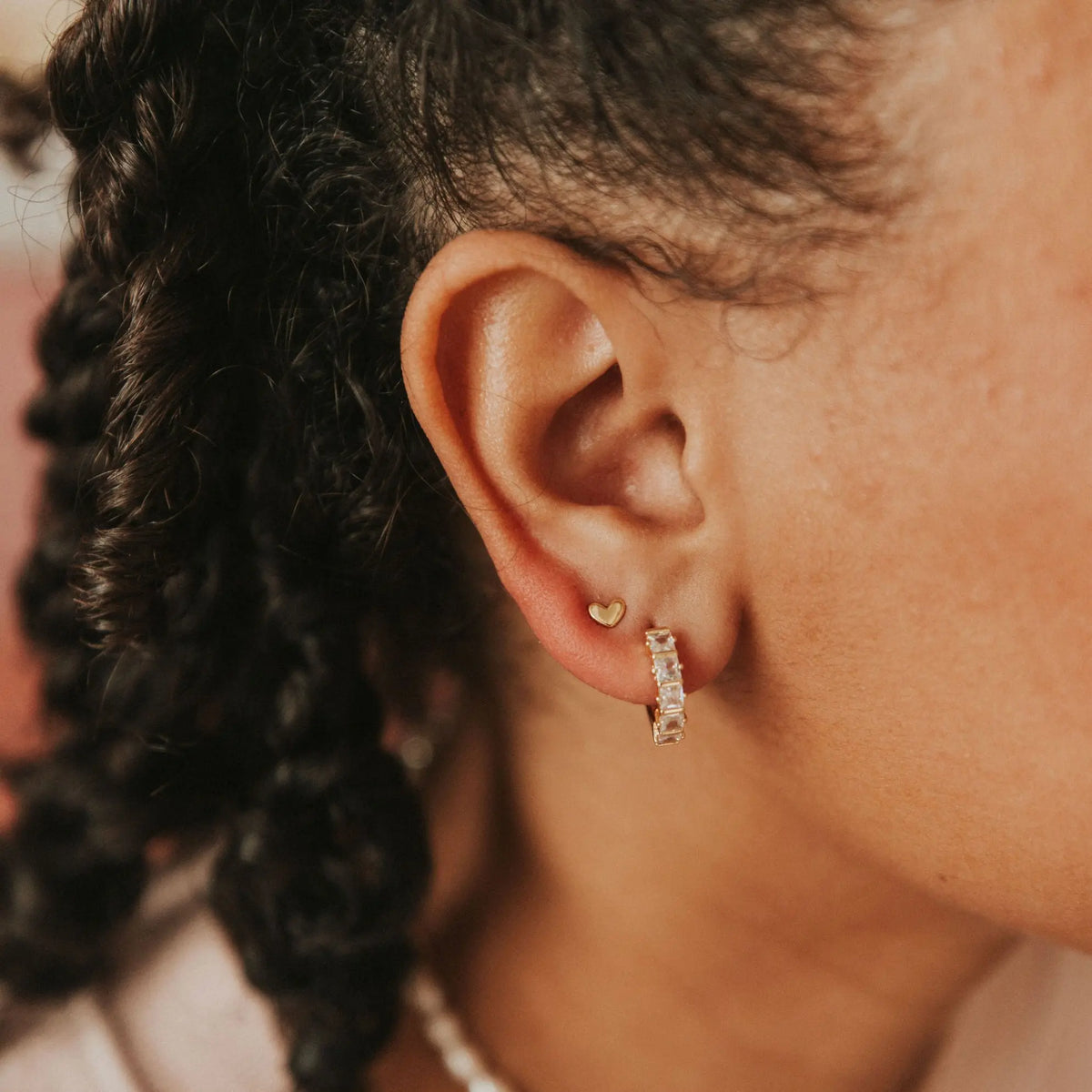 Close-up of an ear wearing a gold hoop earring with a blurred background