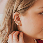 Close-up of a person wearing multiple earrings with a soft background